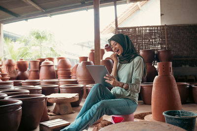 Smiling woman in hijab using digital tablet at work shop