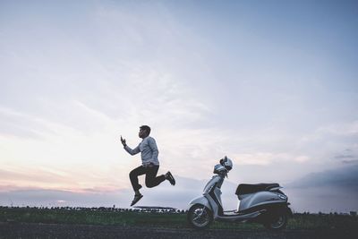 Man cycling on field against sky