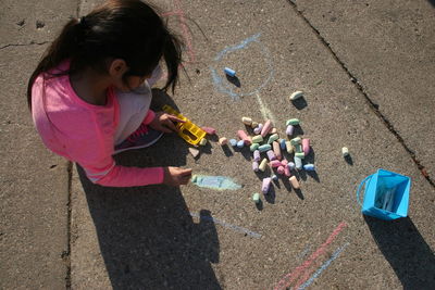 High angle view of girl drawing with chalk on road