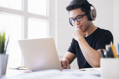 Young collage student using computer and mobile device studying