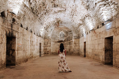 Rear view of female tourist standing in large underground room of an ancient roman palace in split