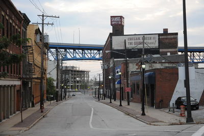 Road by buildings against sky in city