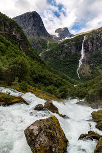 Stream flowing through rocks against sky