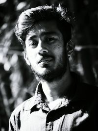 Portrait of young man standing against trees