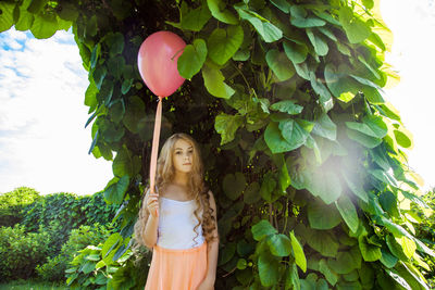 Portrait of a young woman standing with balloon