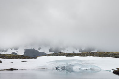 Snow covered landscape with mountain range in background