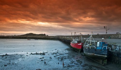 Boats in sea against cloudy sky