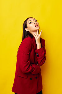 Young woman standing against yellow background