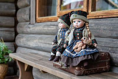 Close-up dolls sitting on suitcase outside house