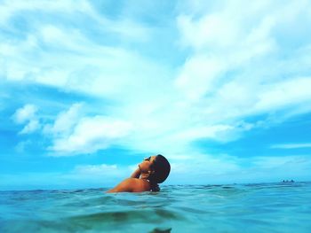 Woman swimming in sea against blue sky
