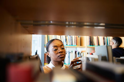 Male and female university students reading books in library