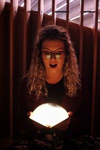 Portrait of young woman sitting in illuminated room