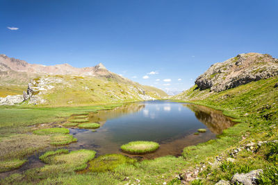 Scenic view of lake and mountains against blue sky