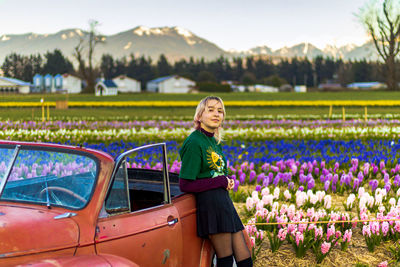 Side view of young woman sitting on car