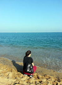 Rear view of man sitting on beach