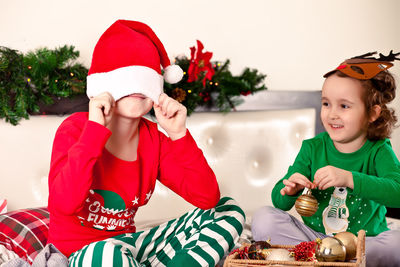 Portrait of siblings playing with christmas tree