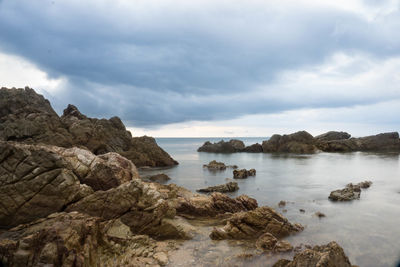 Rocks on sea shore against sky