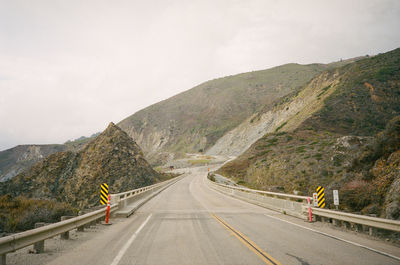 Empty road by mountain against sky