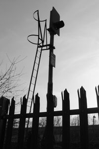 Low angle view of fence on wooden post against sky