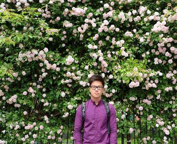 Portrait of handsome young man standing against flowering plants