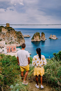 Rear view of people looking at sea against sky