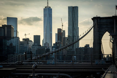 Brooklyn bridge against one world trade center in city at dusk