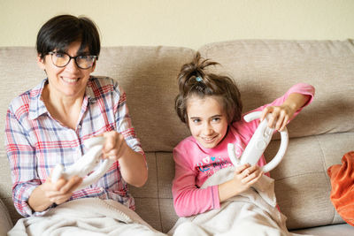 Mother and daughter sitting on sofa