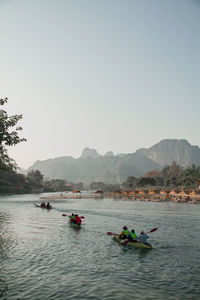 People on boat in river against clear sky