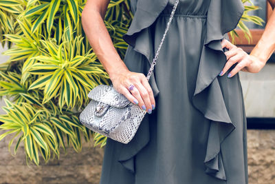 Midsection of woman holding umbrella standing outdoors