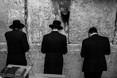 Rear view of men standing against wall