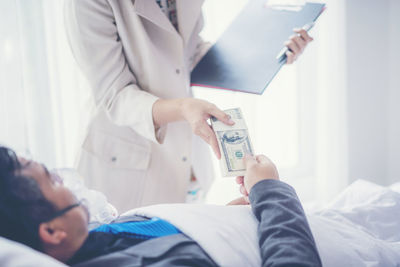 Hospitalized businessman giving money to colleague at hospital