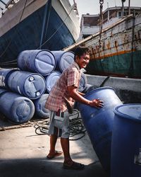 Full length of smiling man holding barrel while standing on land