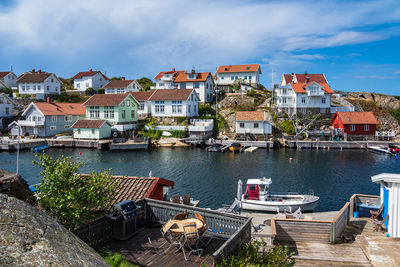 Sailboats moored on river by buildings against sky