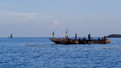 People fishing in sea against sky