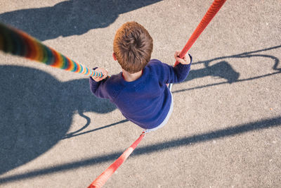 High angle view of boy hanging on rope at playground