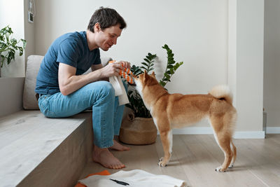 Funny adult man playing with a homemade dog toy with his favorite furry dog friend