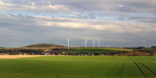 Wind energy business. wind turbine closeup with blue sky, green grass and village