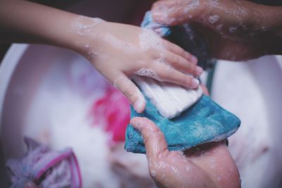 Cropped image of child helping parent while washing textile