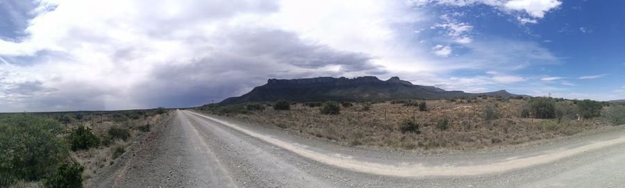 Road by mountains against sky