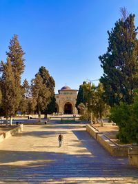 People walking in park against clear blue sky