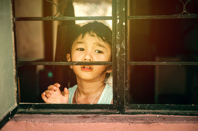 Sad girl looking through window