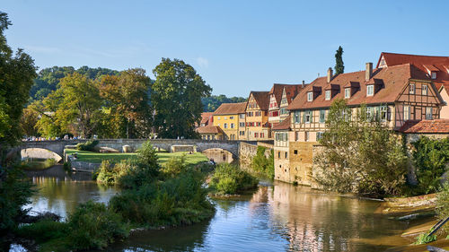 Arch bridge over river by buildings against sky