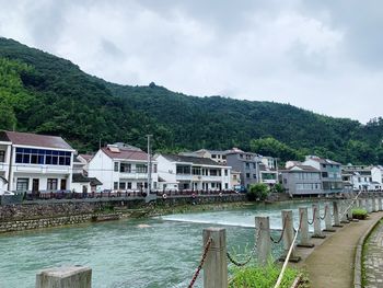 Buildings by river against sky