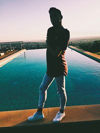 Man standing by swimming pool in sea against clear sky