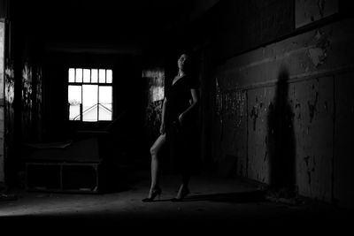 Side view of woman standing in abandoned room