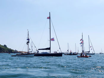 Sailboats sailing on sea against clear sky