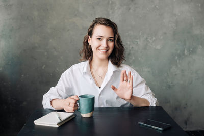 Portrait of young woman using mobile phone while sitting on table