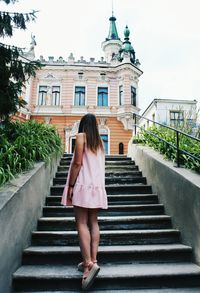 Rear view of woman standing on staircase against building