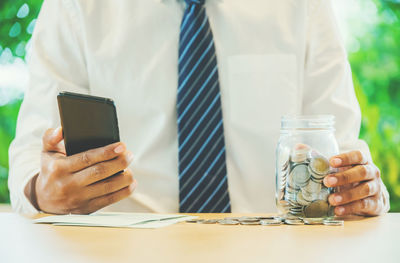 Midsection of man holding mobile phone on table