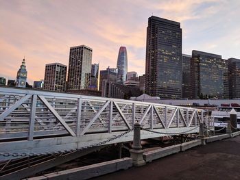 Modern buildings in city against sky during sunset